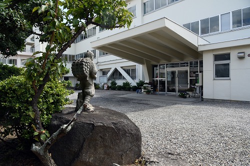 幡豆中学校の玄関と、木々や石像のある前庭